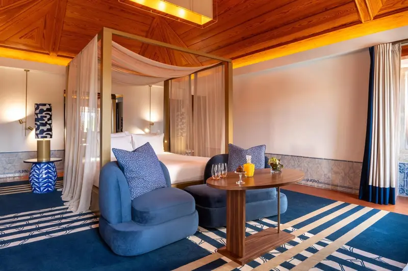 Une chambre lumineuse avec un lit à baldaquin et un coin salon.