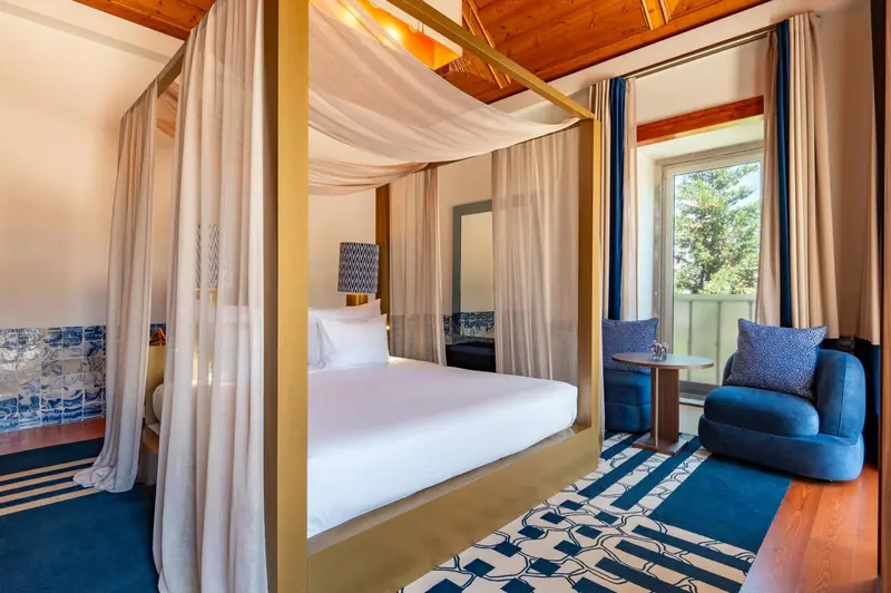 Une chambre lumineuse avec un lit à baldaquin et un coin salon.