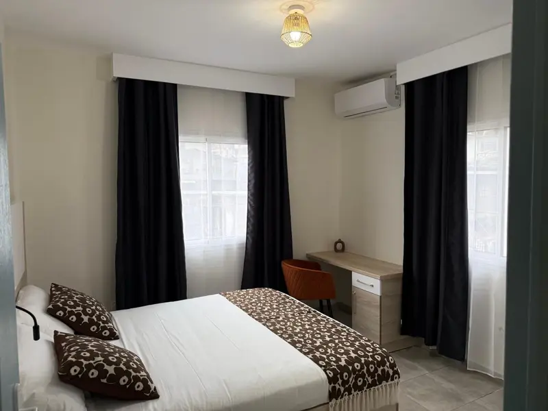 Une chambre lumineuse avec un lit double et un bureau.
