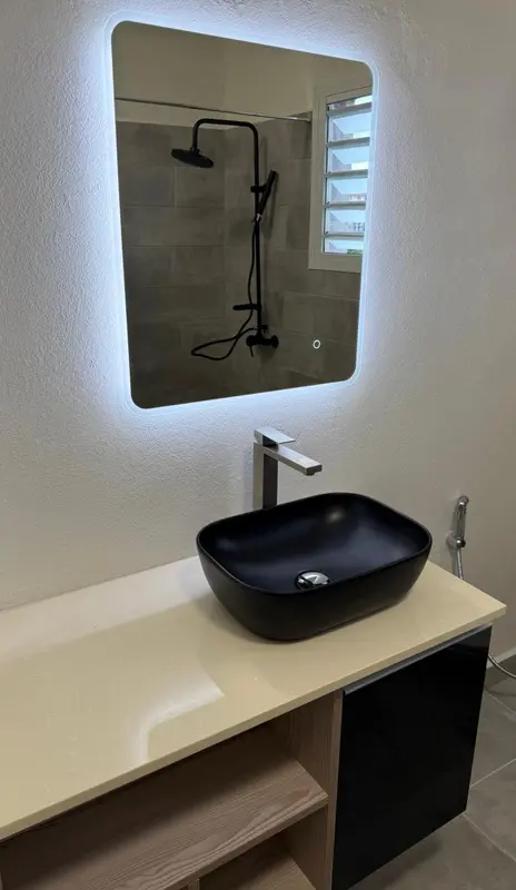 Un lavabo moderne avec un grand miroir lumineux.