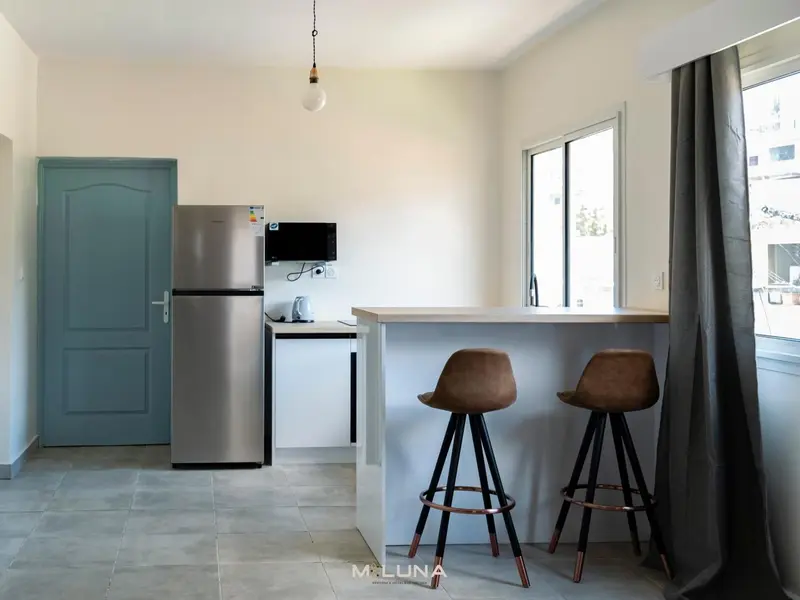 Une cuisine moderne avec un comptoir bar et deux tabourets.
