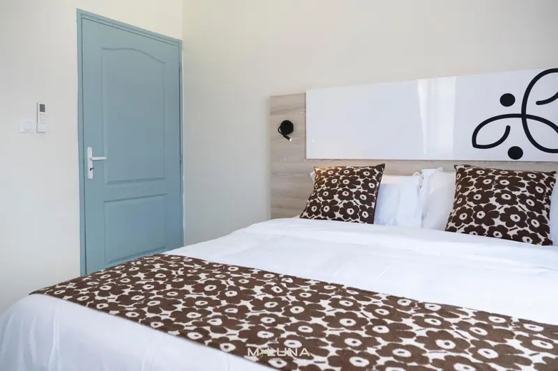Une chambre lumineuse avec un grand lit recouvert d'une courtepointe à motifs.