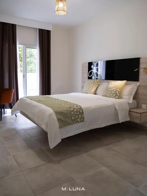 Une chambre lumineuse avec un grand lit recouvert d'une courtepointe.