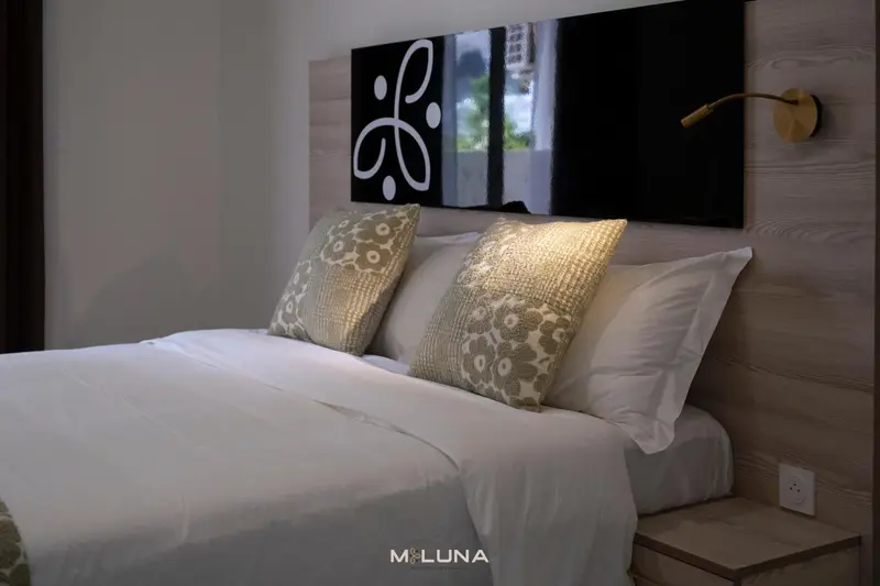 Un lit double est dispose dans une chambre avec une decoration murale et des coussins.