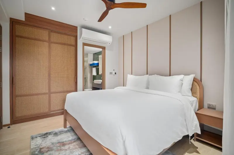 Une chambre lumineuse avec un grand lit et un dressing en bois.