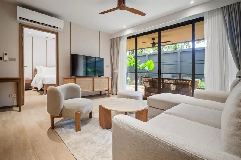Espace de vie intérieur lumineux avec canapés et accès à une terrasse.