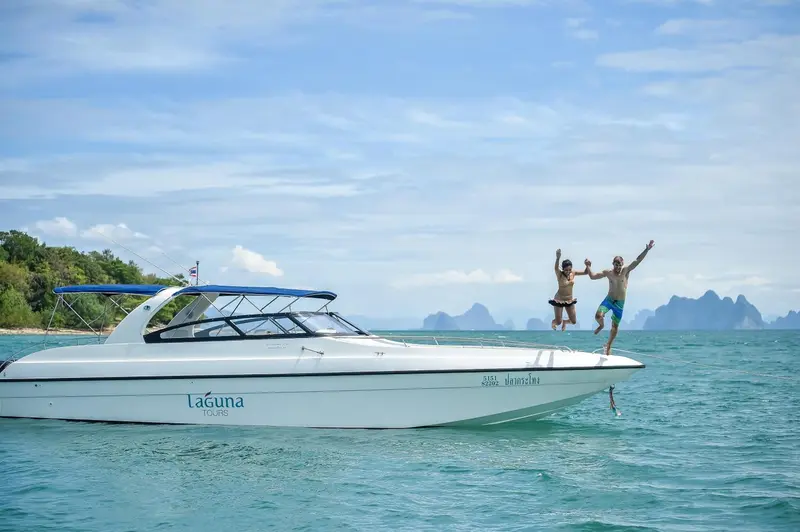 Une personne saute d'un bateau en mer turquoise.