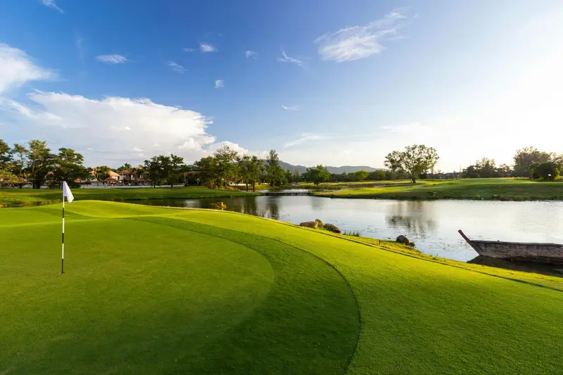 Un terrain de golf verdoyant s'étend jusqu'à un plan d'eau bordé de végétation.