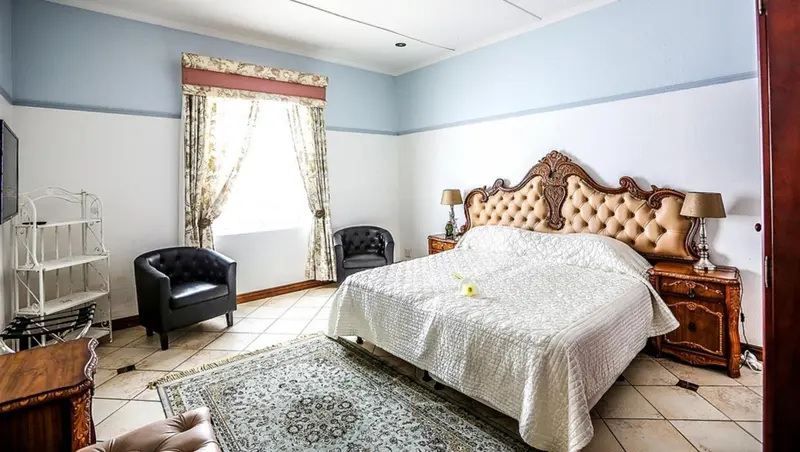Une chambre lumineuse avec un grand lit et des fauteuils.