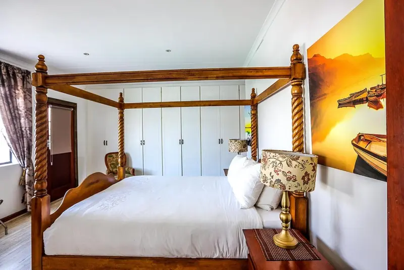 Une chambre avec un grand lit à baldaquin et une décoration murale représentant un paysage marin.