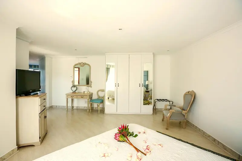 Une chambre lumineuse avec un lit décoré de fleurs et un coin coiffeuse.