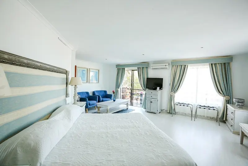 Une chambre lumineuse avec un grand lit et un coin salon.