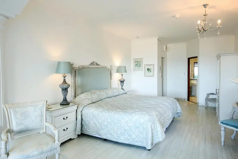 Une chambre lumineuse avec un grand lit à baldaquin et un fauteuil.