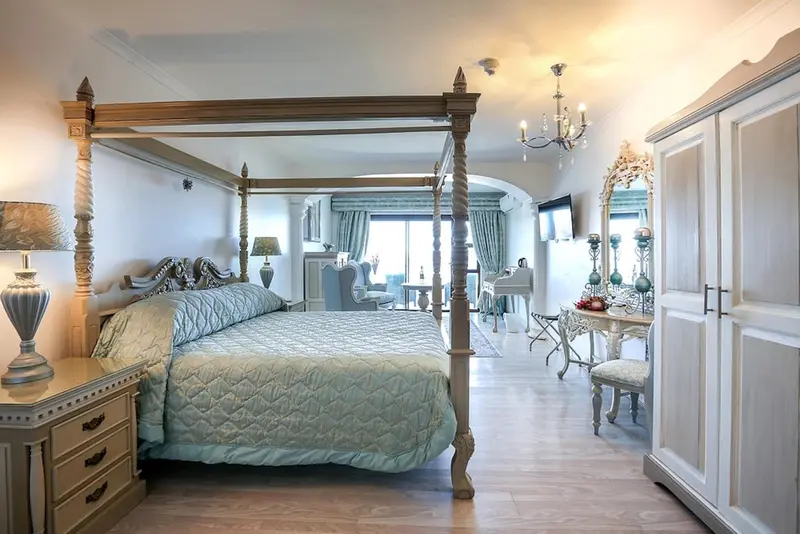 Une chambre lumineuse avec un grand lit à baldaquin et un mobilier ancien.