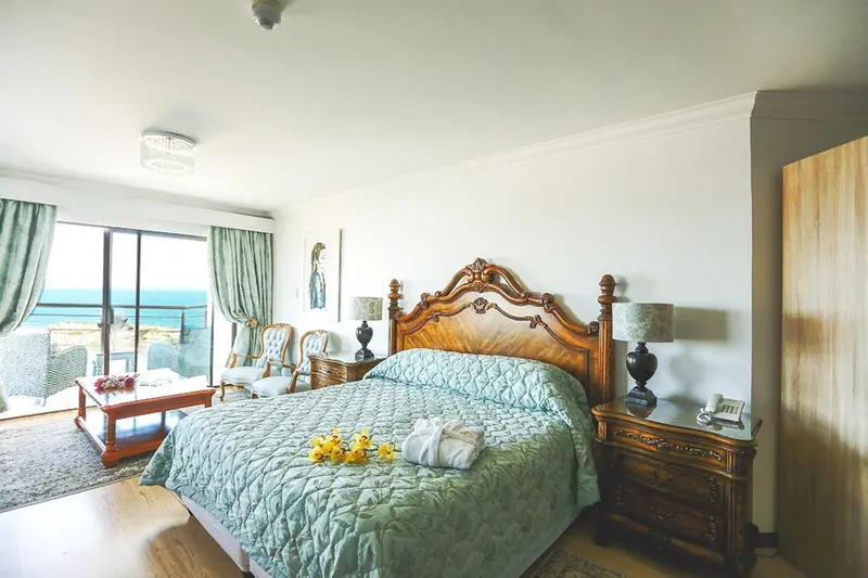 Une chambre lumineuse avec un grand lit à baldaquin et une vue sur la mer.