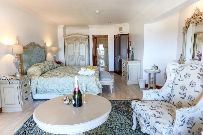 Chambre spacieuse avec un lit à baldaquin et un coin salon.