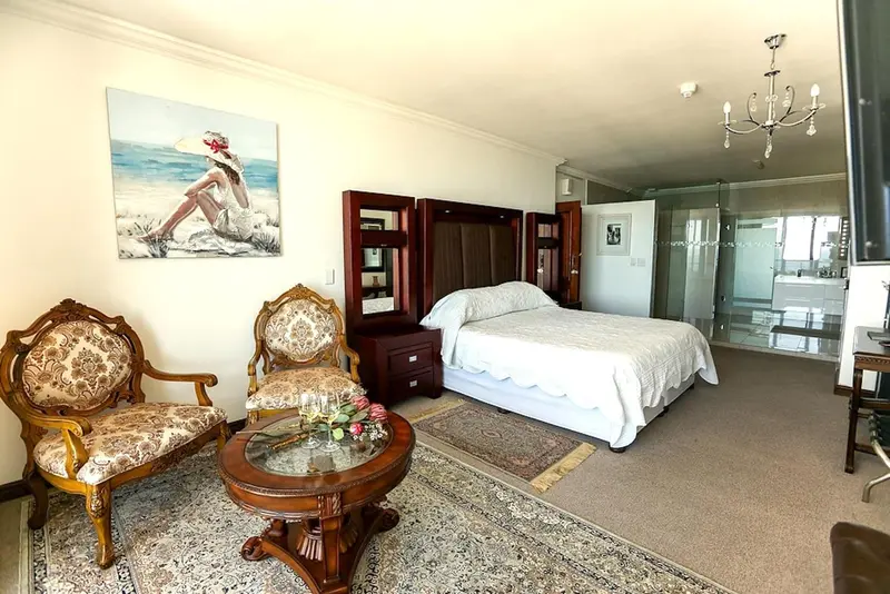 Une chambre lumineuse avec un grand lit et un coin salon.