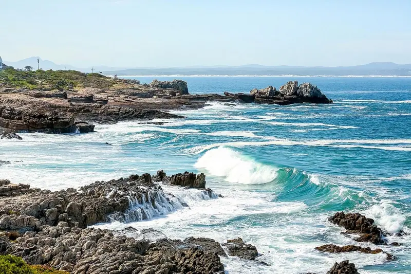 Vagues déferlant sur une côte rocheuse ensoleillée.