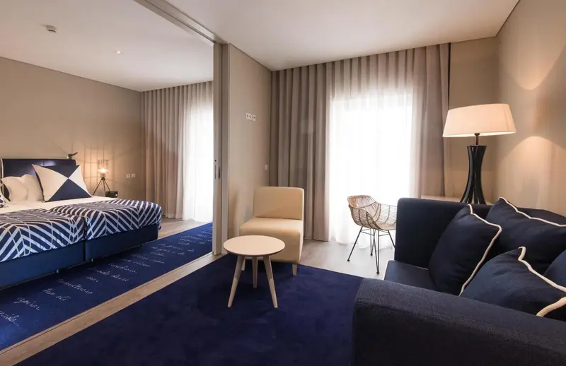 Une chambre moderne avec un lit double, un canapé et un fauteuil.