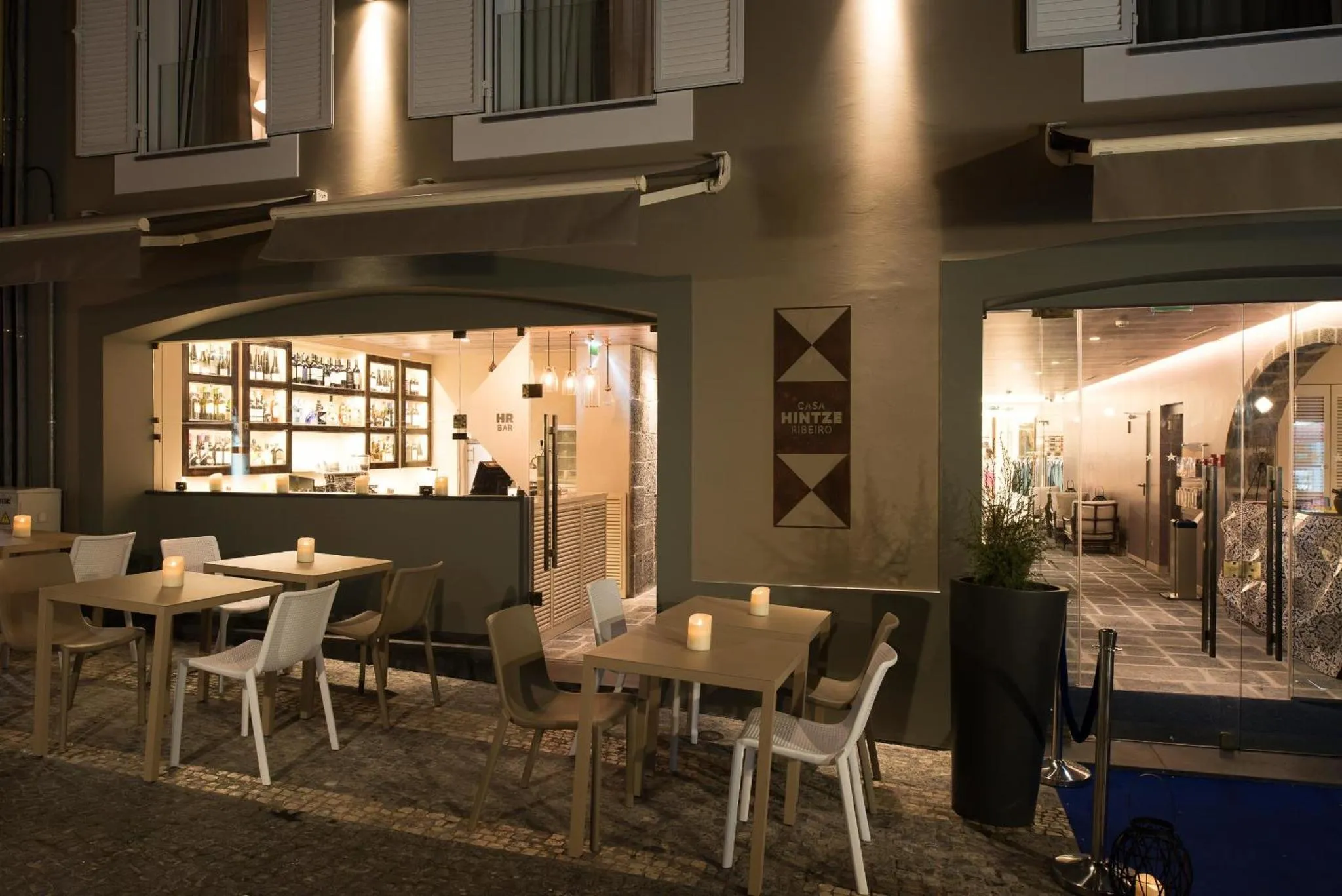Terrasse de restaurant avec tables éclairées à la bougie et bar en fond.