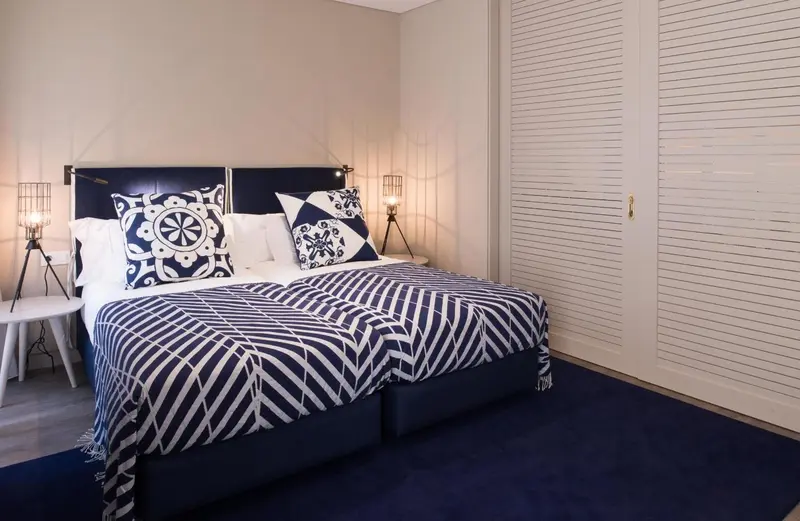Une chambre avec un grand lit recouvert d'une courtepointe bleue et blanche.