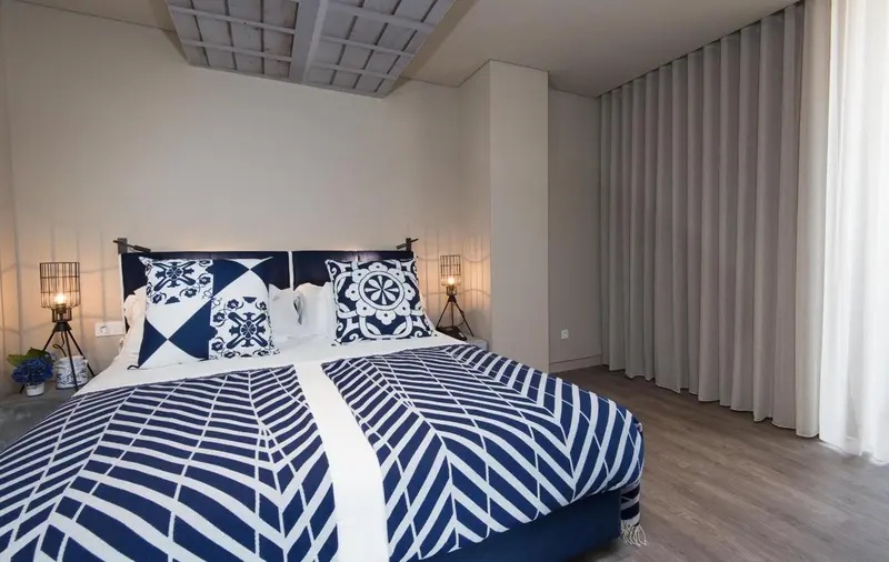 Une chambre lumineuse avec un grand lit décoré de motifs bleus et blancs.