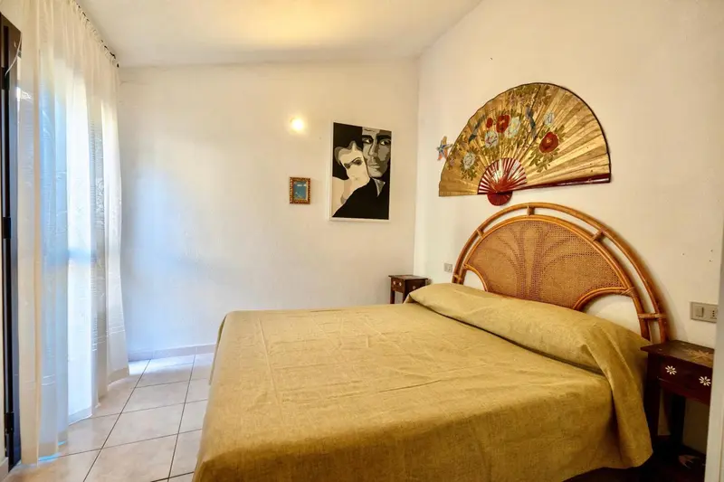 Une chambre lumineuse avec un grand lit recouvert d'une couverture jaune.