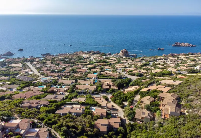 Vue aérienne d'un ensemble de villas et de bâtiments au milieu d'une végétation côtière.