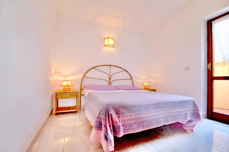 Une chambre lumineuse avec un lit recouvert d'une couverture colorée.