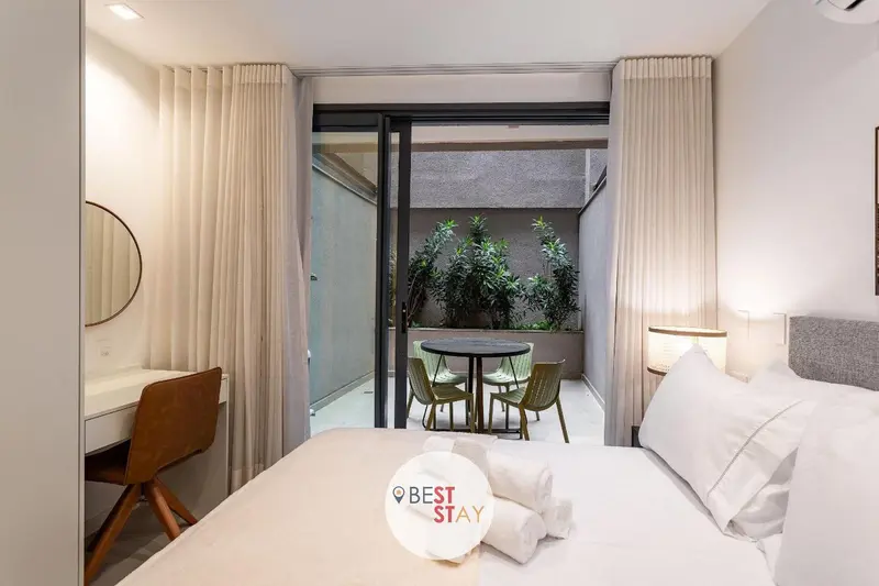 Une chambre lumineuse s'ouvre sur une terrasse avec table et chaises.