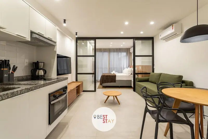 Une cuisine moderne s'ouvre sur un espace de vie avec canapé et lit.