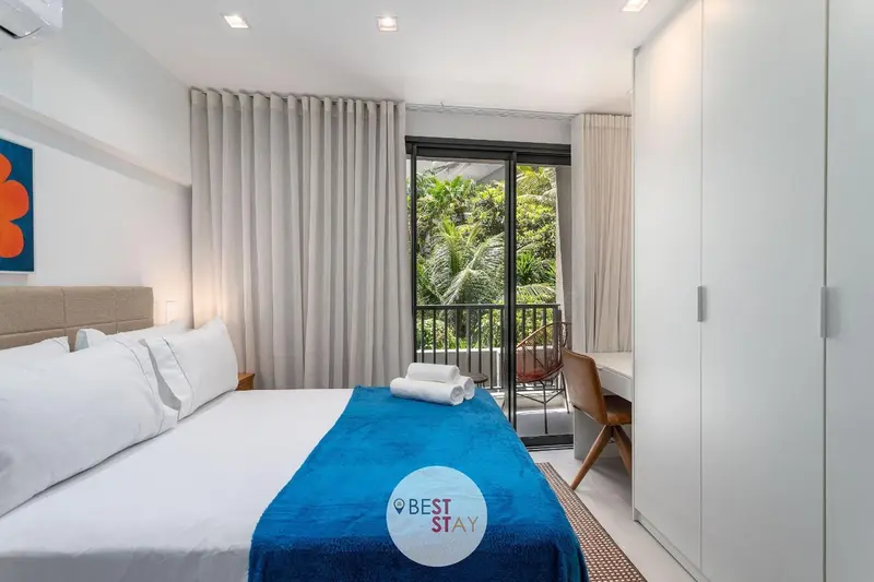 Une chambre lumineuse avec un grand lit et un accès à un balcon.