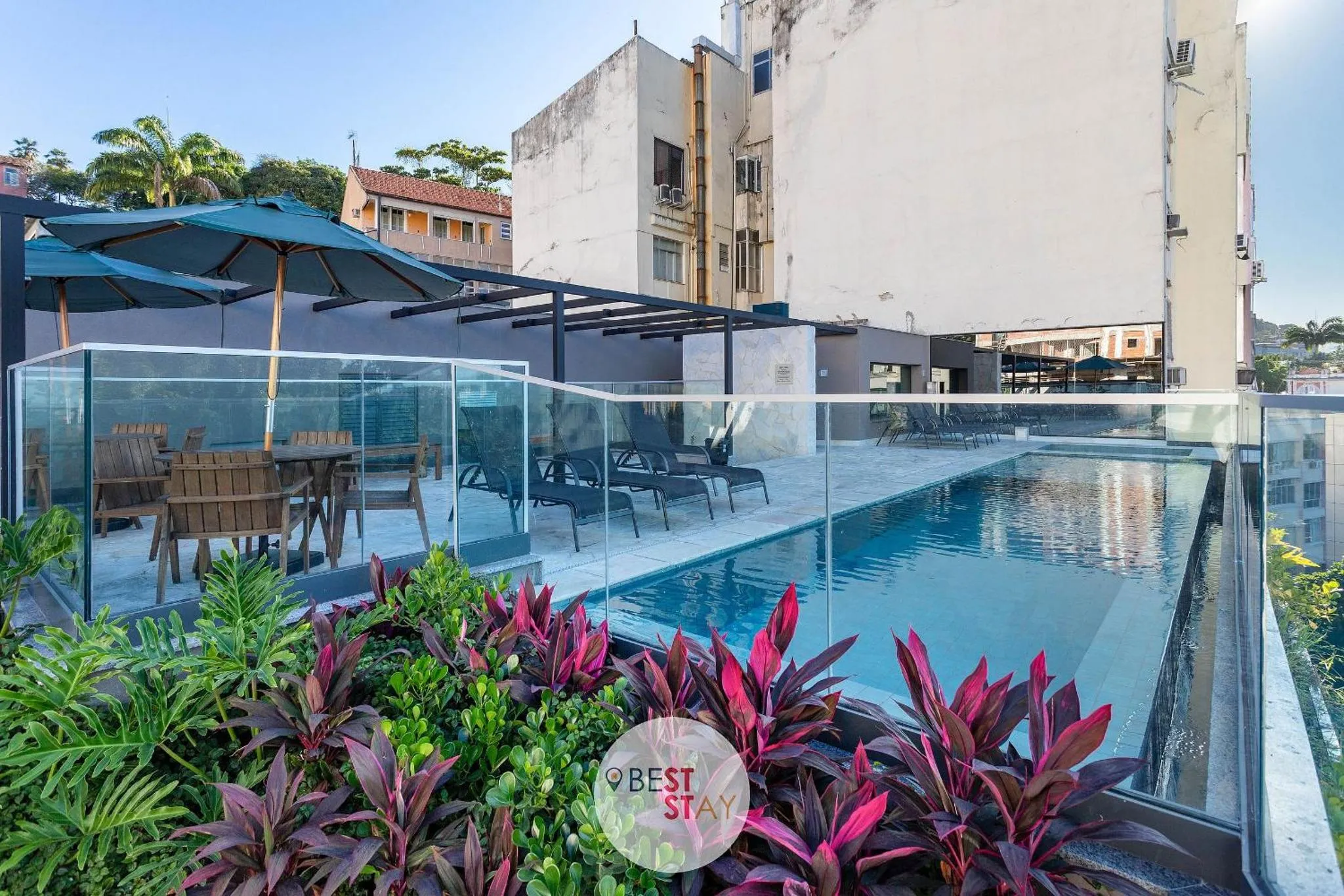Une piscine rectangulaire avec des transats et des parasols sur une terrasse ensoleillée.