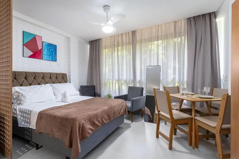Une chambre lumineuse avec un grand lit et un coin repas.