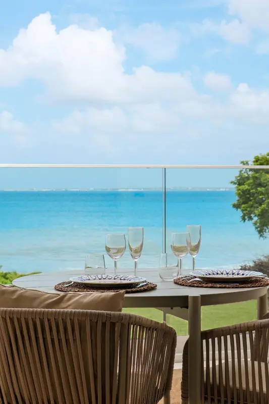 Une table avec des verres de vin est mise en scène sur une terrasse face à la mer.