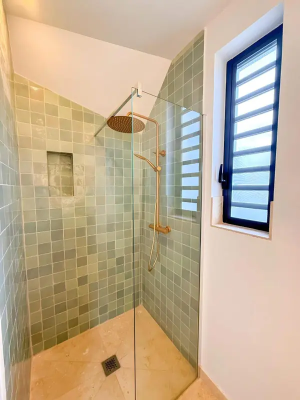 Douche à l'italienne carrelée de vert d'eau avec pommeau doré.