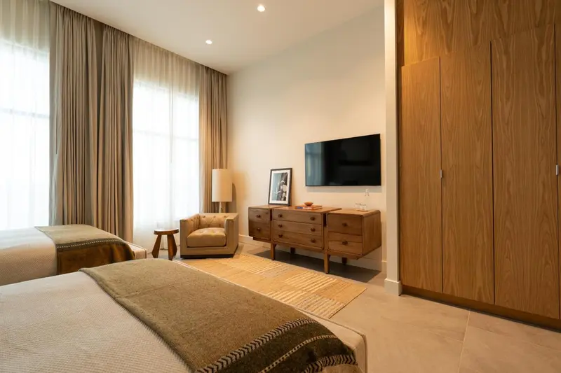 Une chambre lumineuse avec un lit, un fauteuil et une commode.