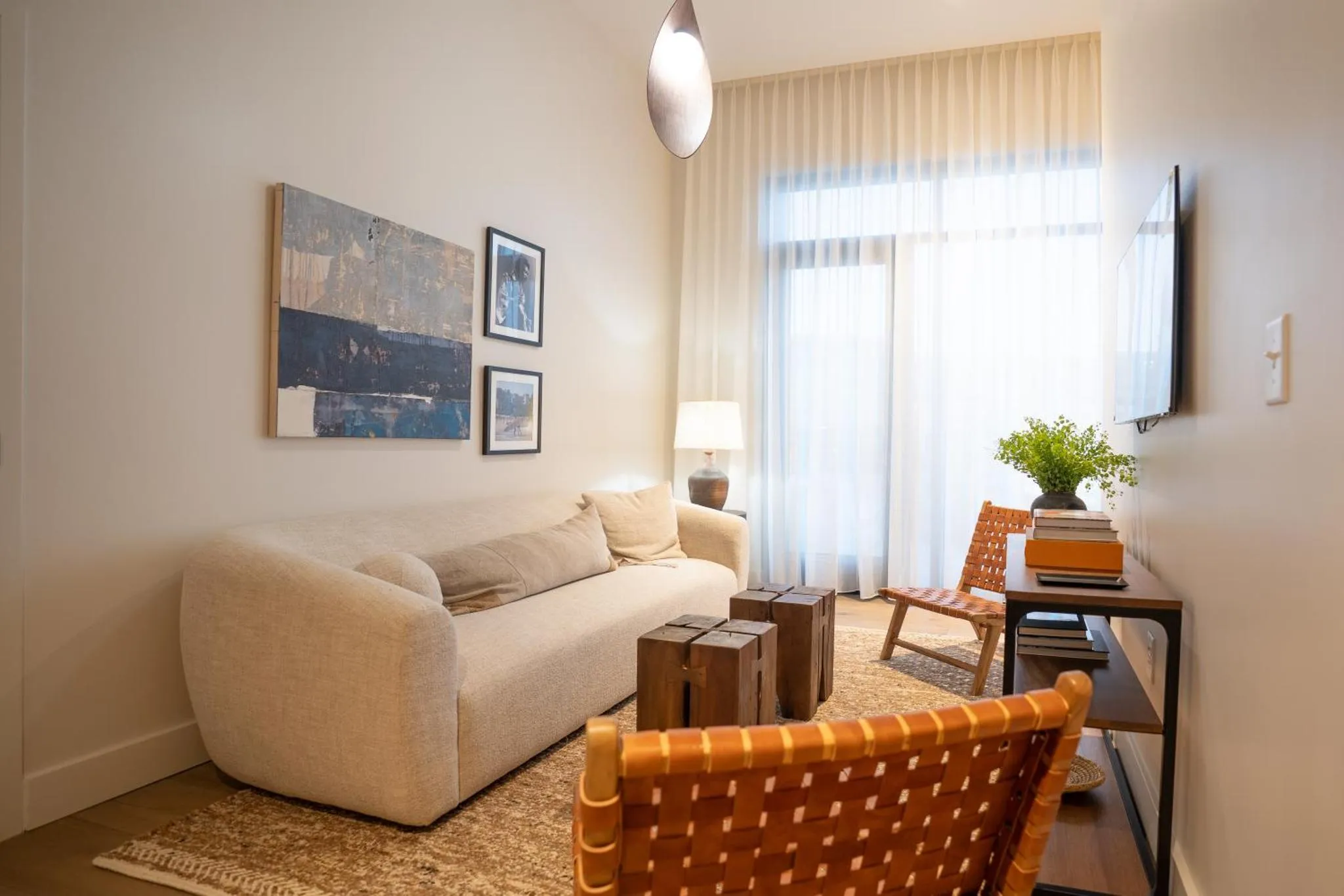 Un canapé beige et une chaise en bois clair composent un espace de détente lumineux.