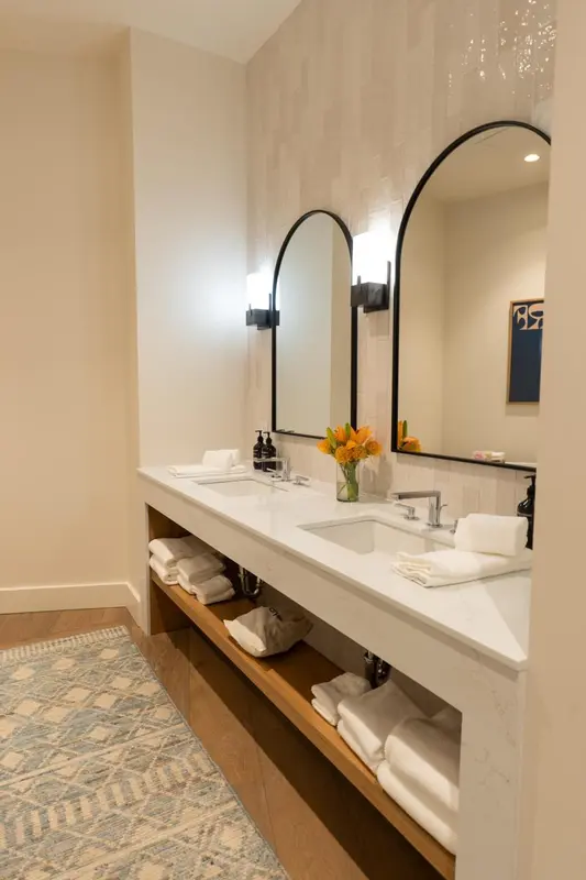 Trois vasques blanches avec miroirs au-dessus dans une salle de bain lumineuse.
