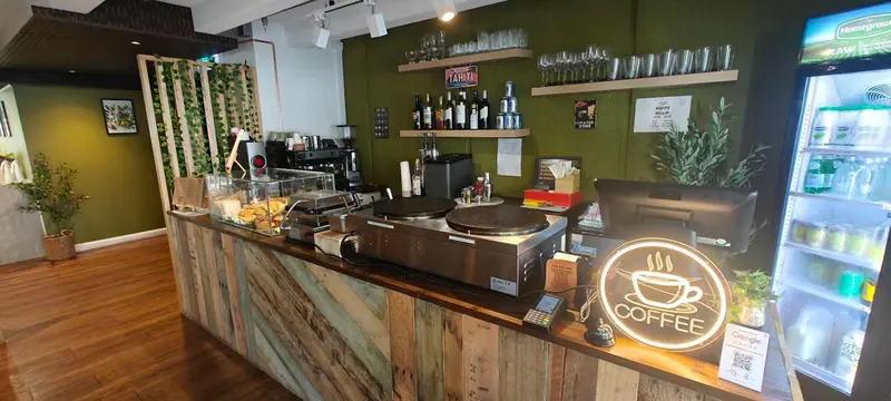 Un comptoir de bar en bois clair avec des boissons et de la pâtisserie.