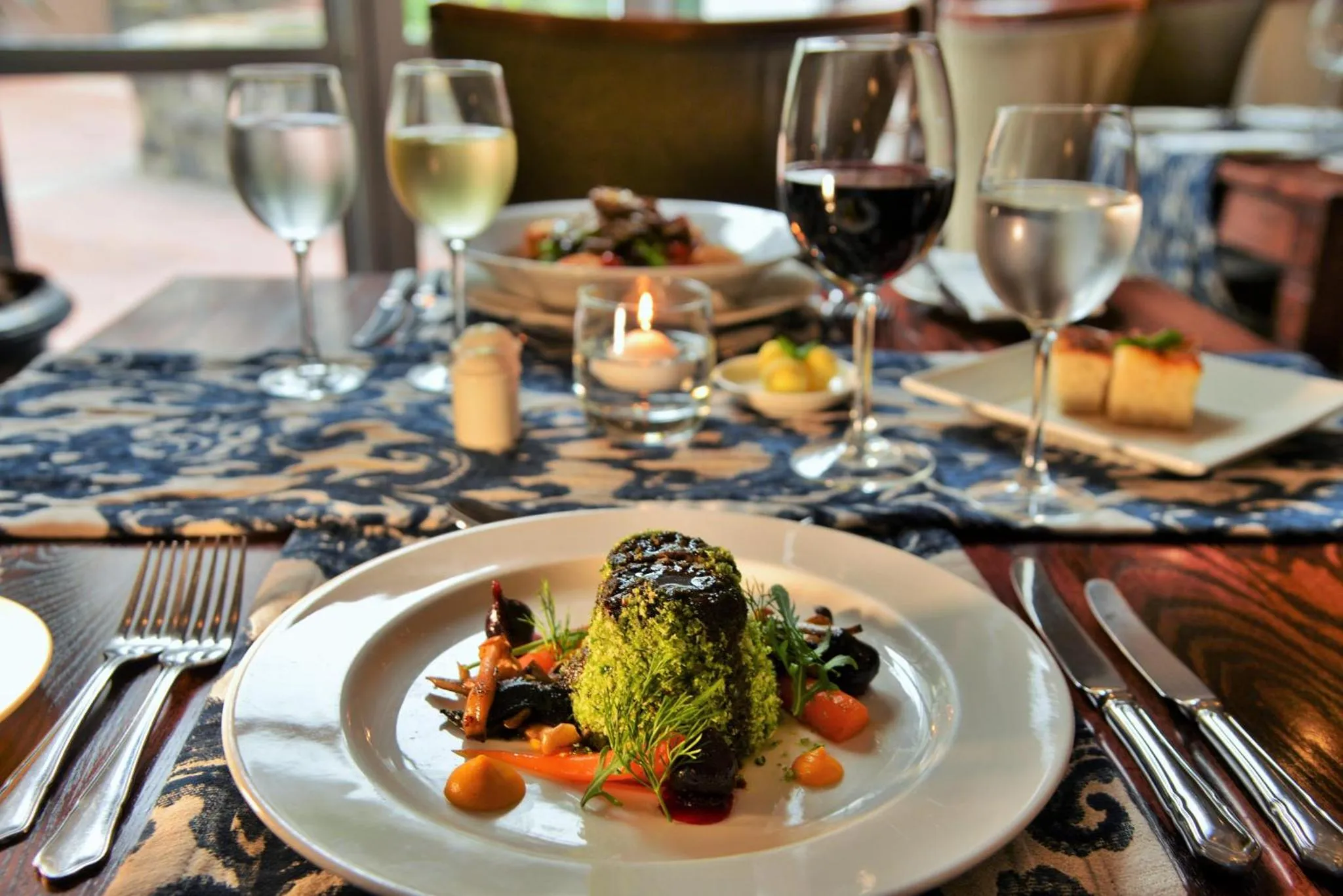 Une table est dressée avec des plats raffinés et des verres de vin.