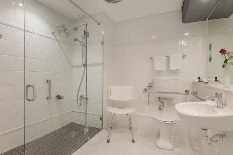 Une salle de bain claire avec douche à l'italienne et lavabo.