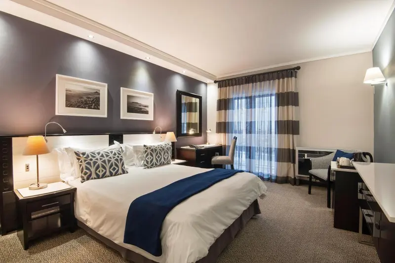 Une chambre d'hôtel avec un grand lit et un bureau près d'une fenêtre.