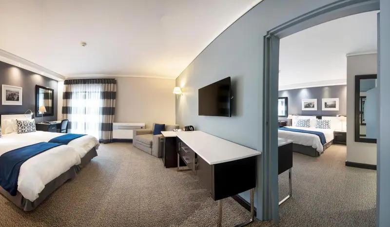 Une chambre d'hôtel lumineuse avec deux lits et un espace bureau.