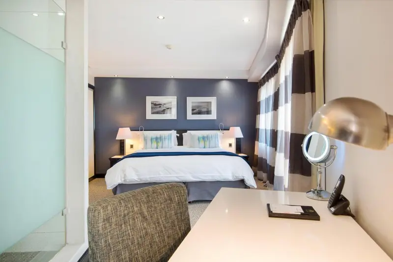 Une chambre lumineuse avec un grand lit et un bureau.