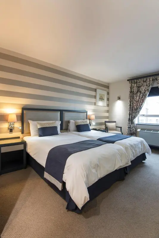 Une chambre avec un grand lit recouvert d'une courtepointe blanche et bleue.