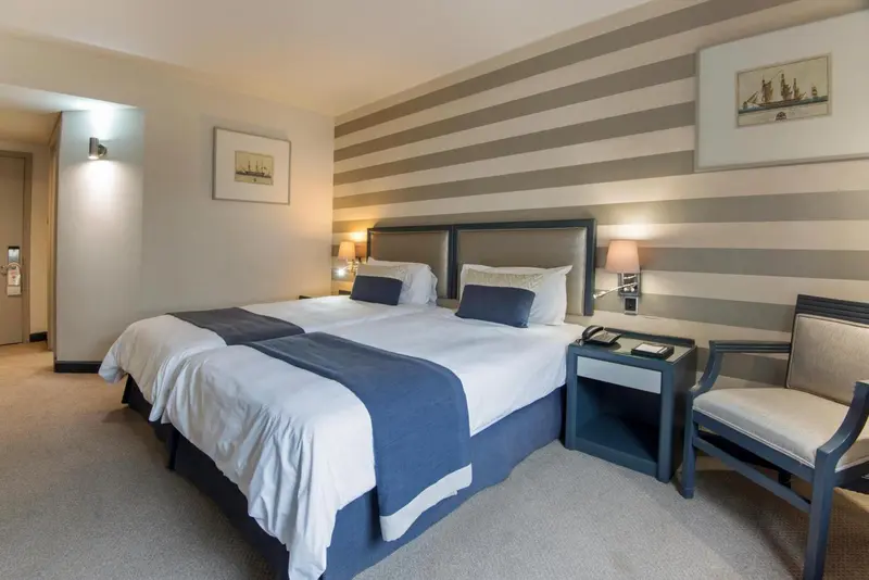 Une chambre d'hôtel moderne avec deux lits simples et un fauteuil.