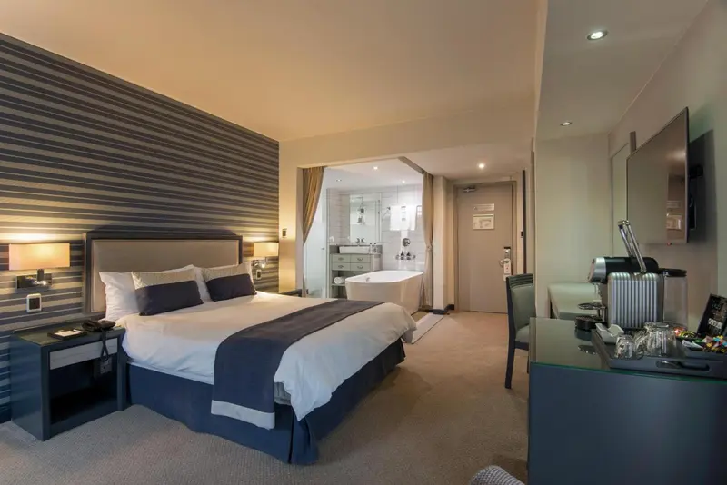 Une chambre d'hôtel moderne avec un grand lit et une baignoire sur pied.