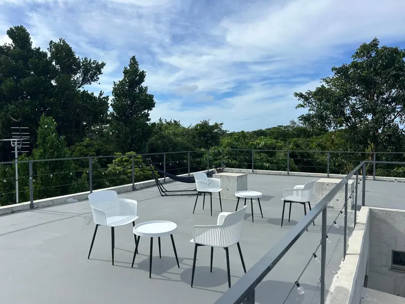 Terrasse aménagée avec mobilier blanc et végétation luxuriante en arrière-plan.
