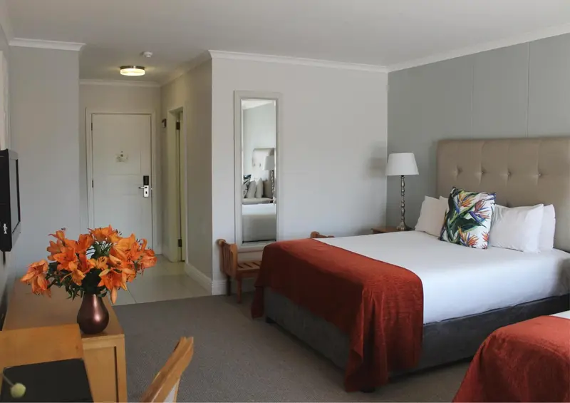 Une chambre d'hôtel lumineuse avec un grand lit et un bouquet de fleurs.